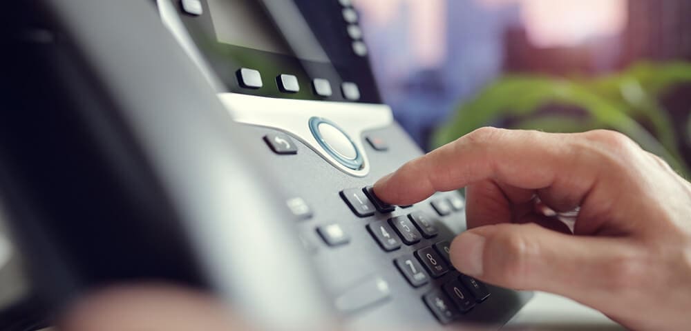 Image of desktop telephone with user.